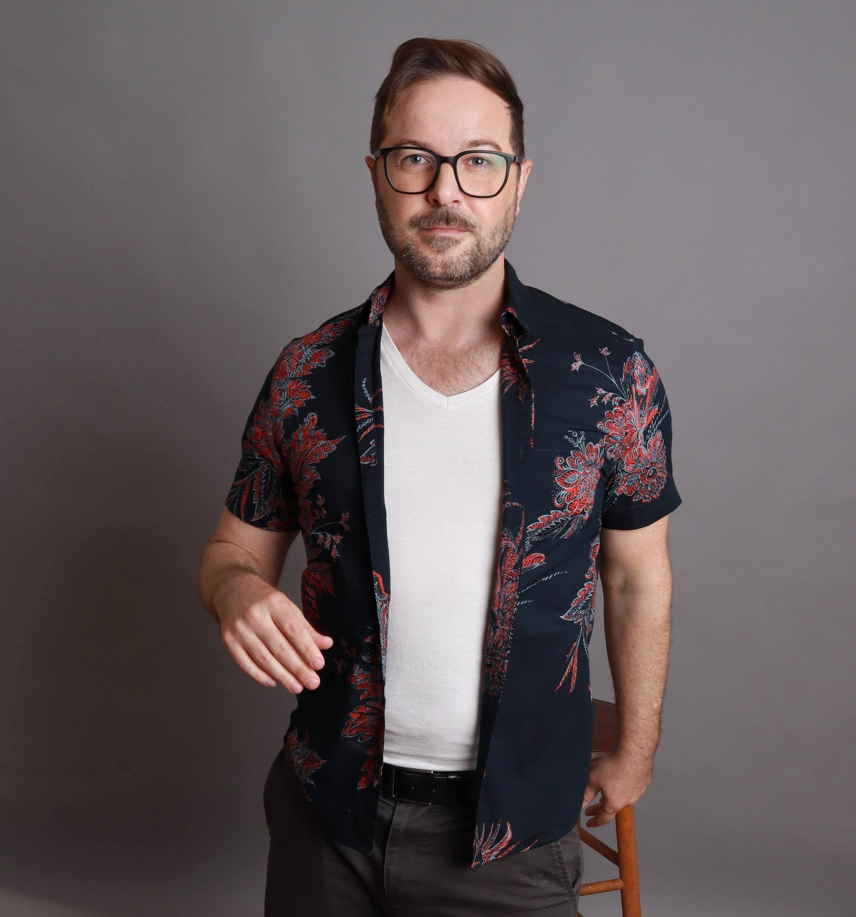Portrait of a model in a dark floral shirt layered over a white tank, textured side-swept hair, Bang Bang Stone grooming work