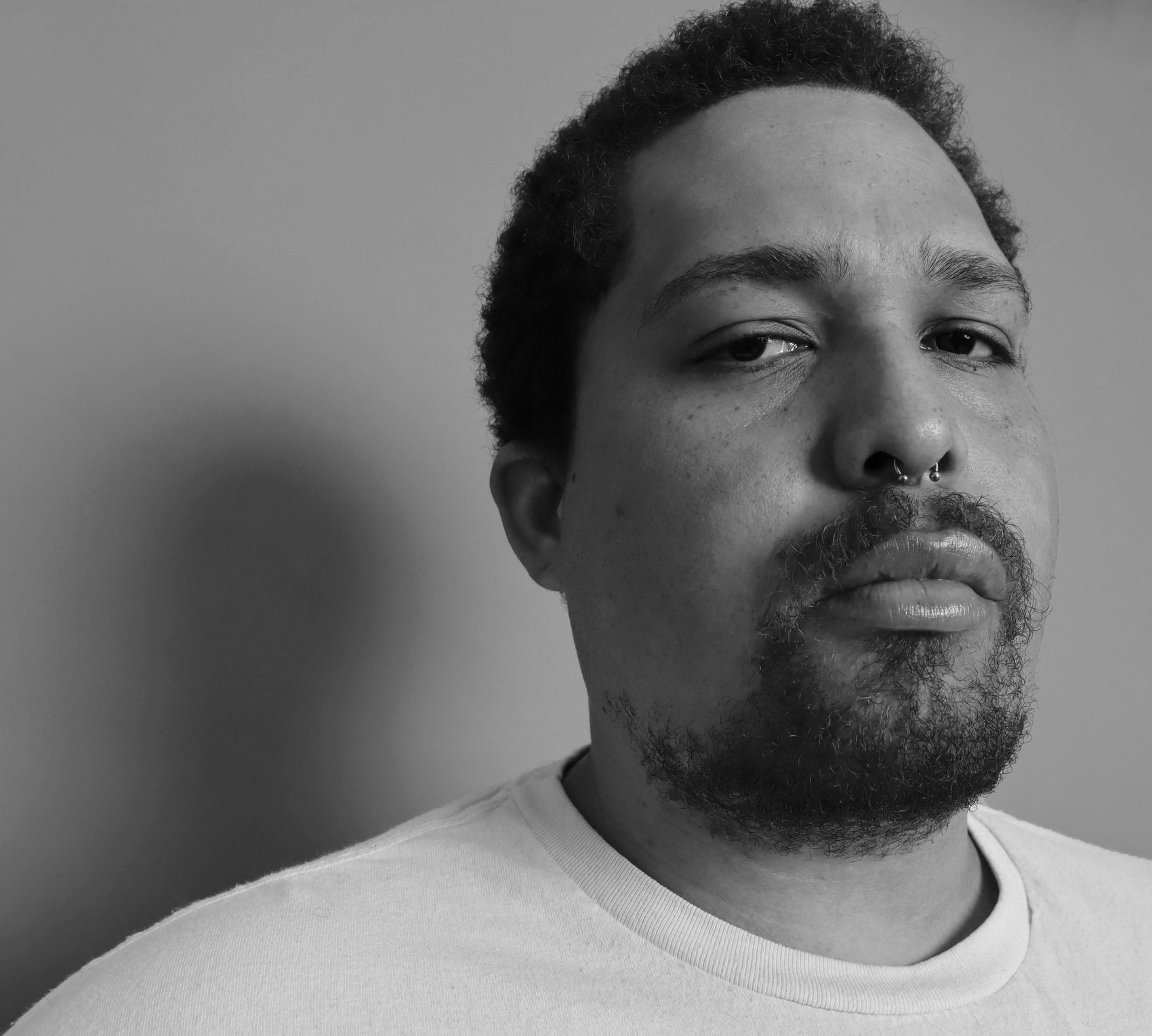Black-and-white close-up of Saafir with a groomed beard and septum piercing, Bang Bang Stone men's grooming