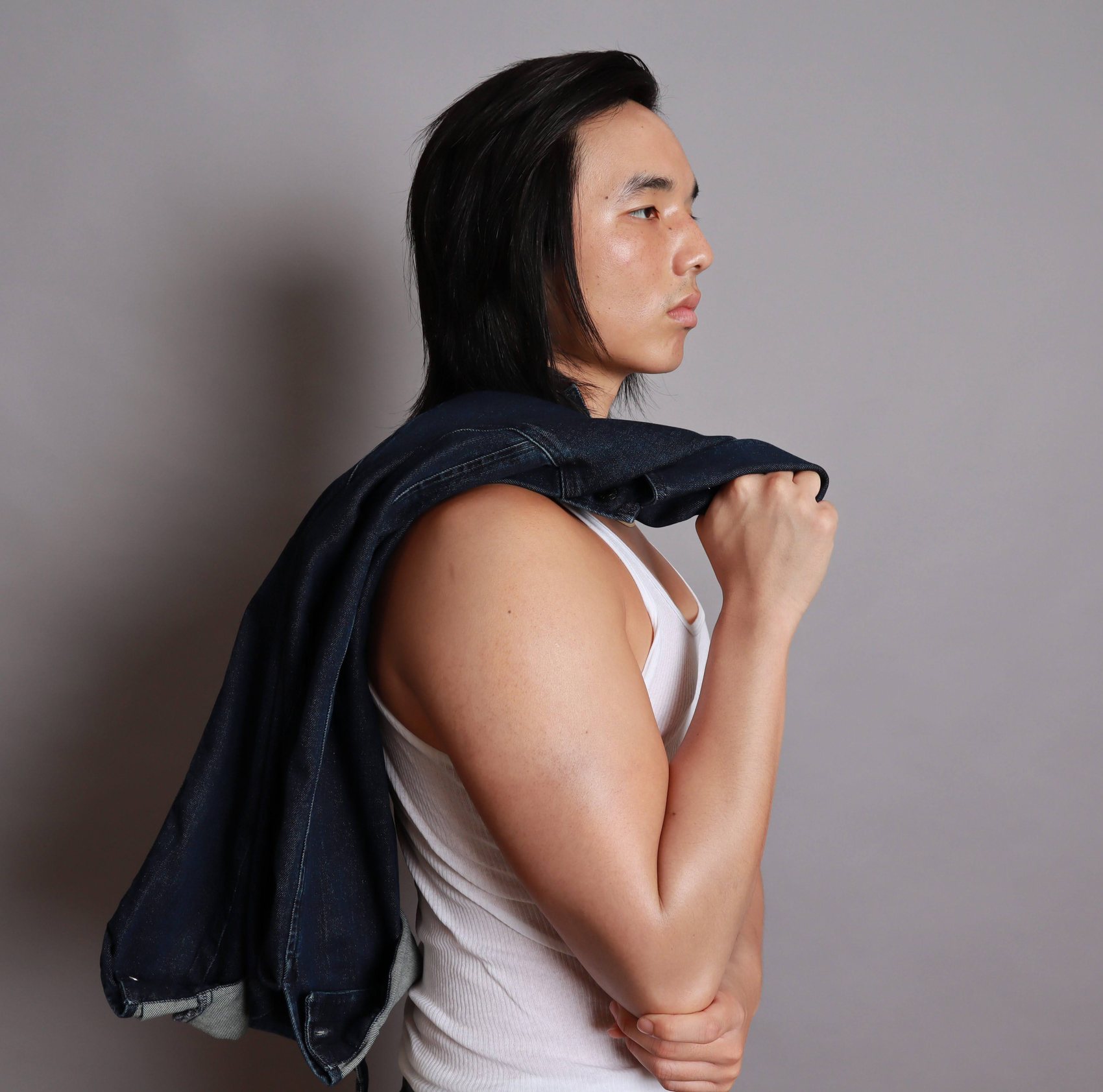 Side-profile portrait with a denim jacket draped over the shoulder and a white tank top, Bang Bang Stone men's grooming